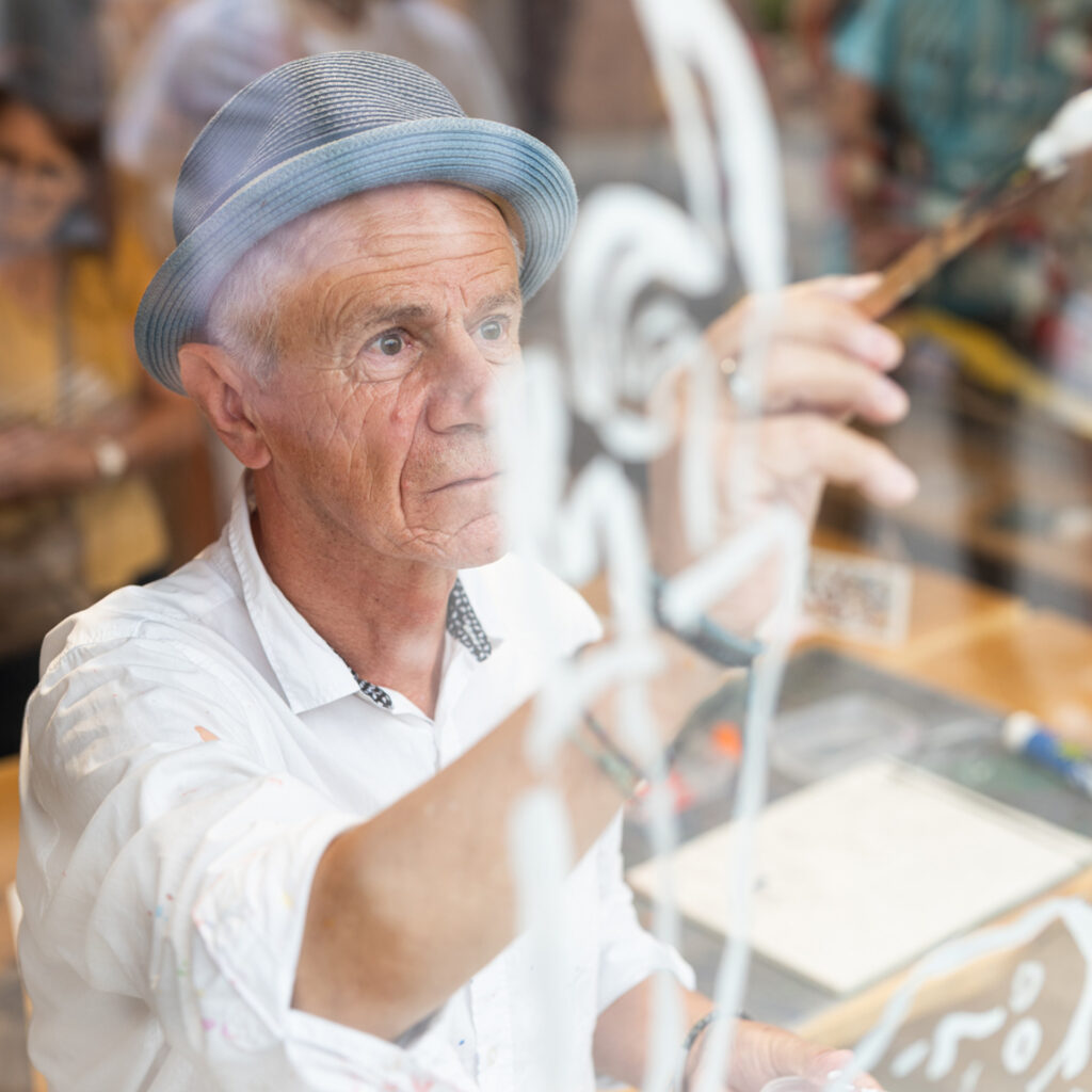 Clair ARTHUR qui peint la vitrine de Atelier-Atelier